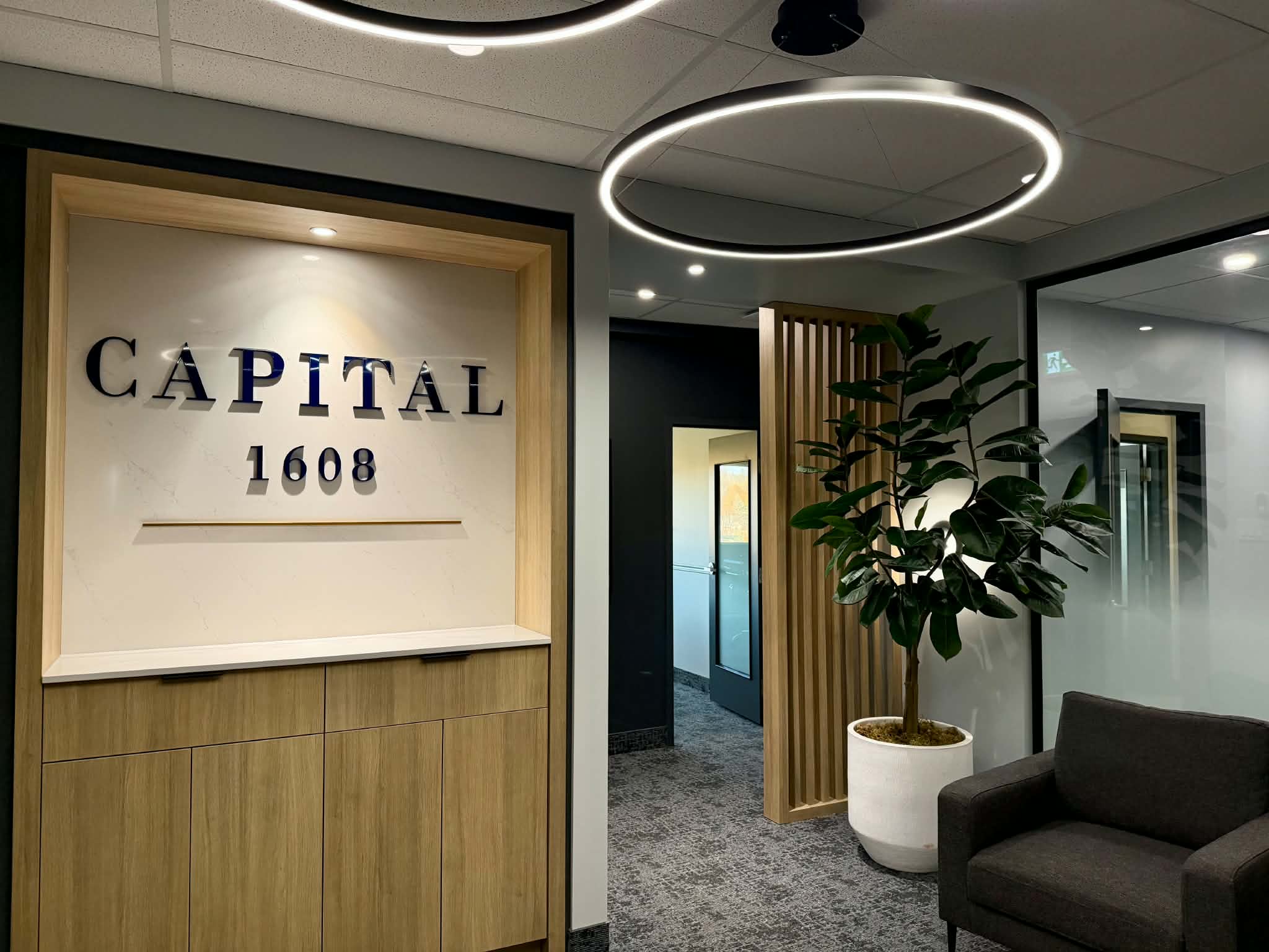 Réception avec enseigne Capital 1608, mobilier en bois et luminaires circulaires